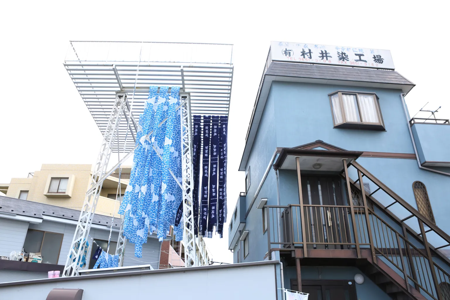 染め上げた1反（約12m）分の手ぬぐいを、折り目をつけないように天日干しするため、２階建ての染工場の屋上には、約15mの高さの櫓が設置されている。