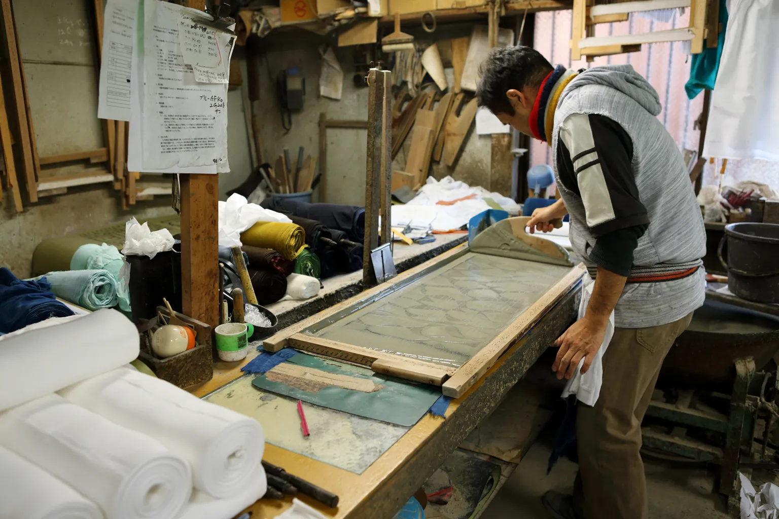 型付を行う「板場」では、職人が木ベラを使い、型紙の上に糊を引いていく。均一な塗りを保つ繊細な加減は体で覚えるしかないのだという。