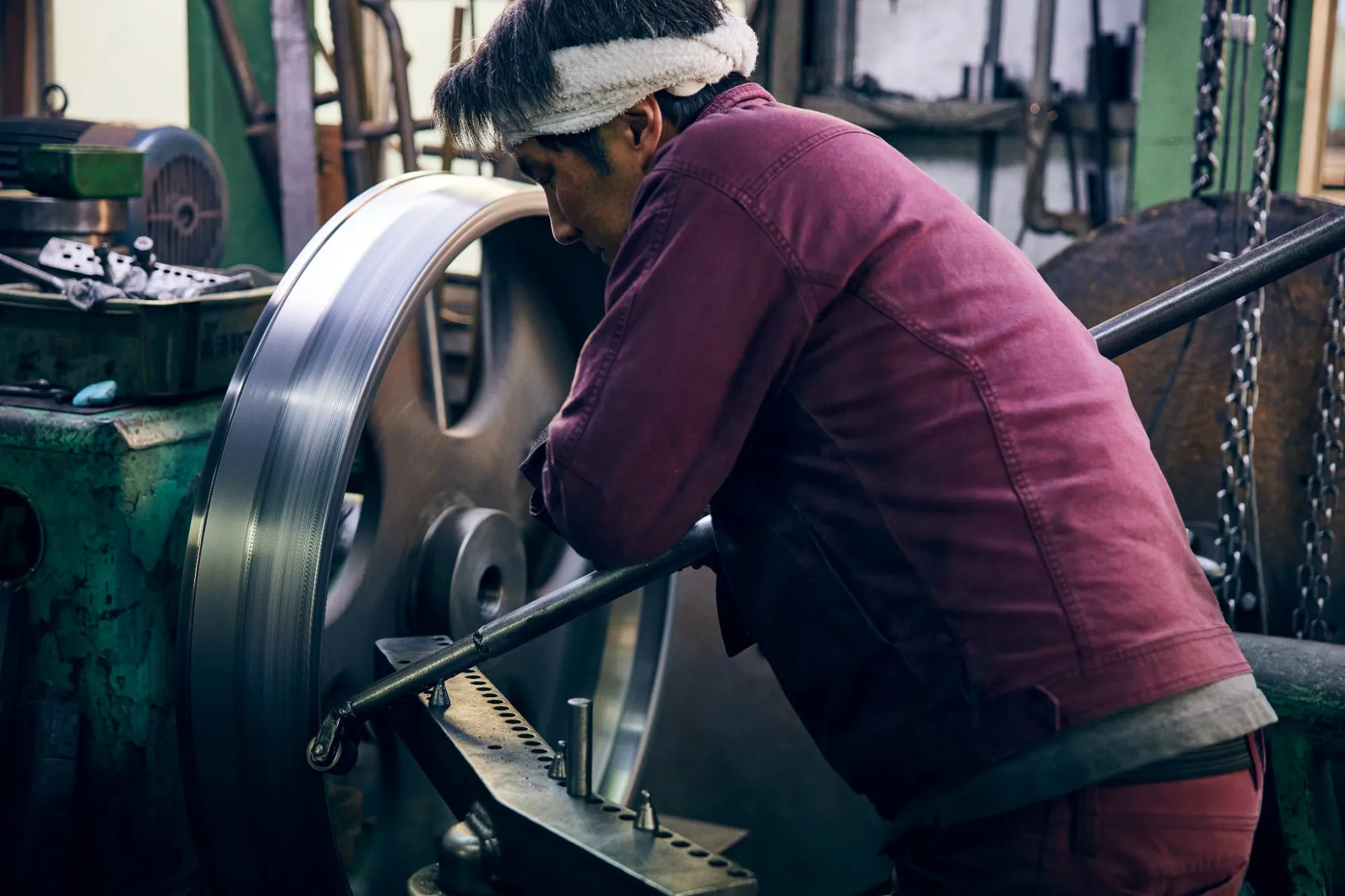 大型時計用の部品の絞り加工作業。工場内で作業するのは屈強な職人さんたち。日々の絞り作業が筋トレになるのだそう。