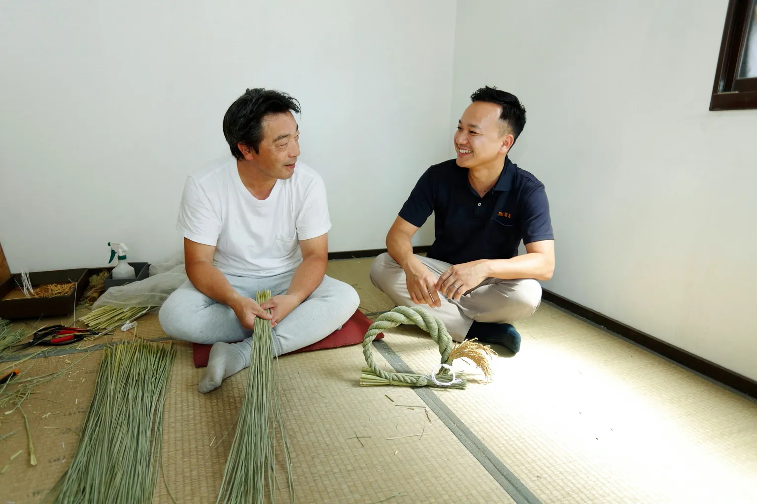 ときにはお酒を片手に、しめ縄について語り合うという岸野さん（左）と首代さん（右）。伝統技術を守りつつ、新しい挑戦を続けるふたりの姿勢がわら文化の未来を支えている。