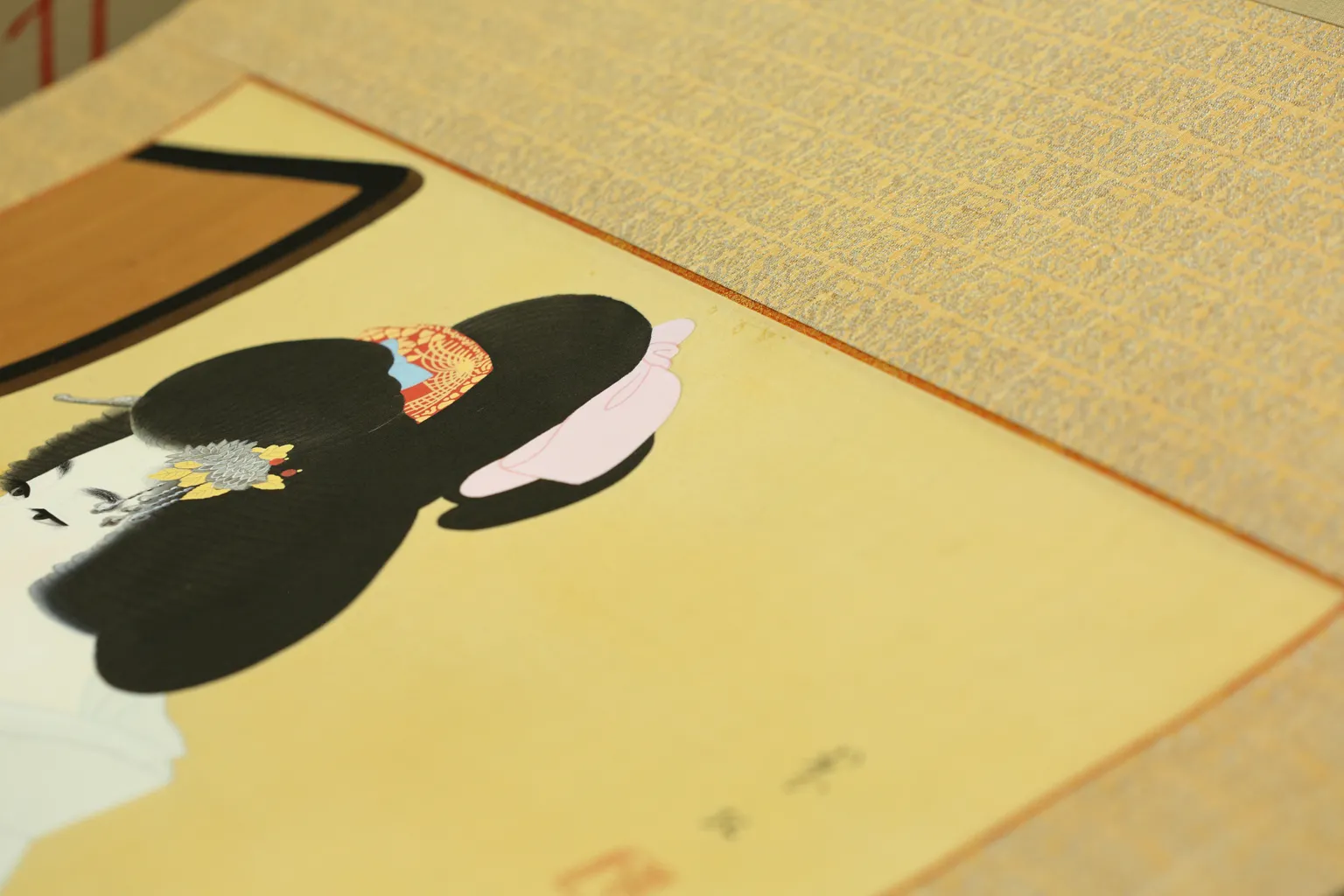 日本画を表装した掛け軸。柄の裂地の際に、美人画にあるかんざしと似た柿色を差し込むことで、メリハリが生まれて掛け軸に凜とした表情を作り出す。
